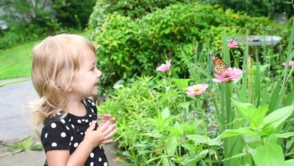 cute caucasian toddler little girl is playing with monarch butterfly. kids exploring outdoors. child