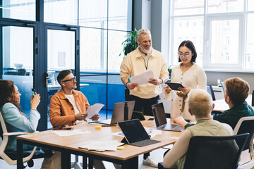 Fototapete - Group of professional startuppers discussing business ideas during collaborative meeting for brainstorming in office interior, successful male and female with technology talking about trade project