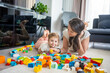 © dtatiana - Little girl play with constructor toy on floor in home with mom or woman babysitter, educational game, family at home spend leisure activities time together concept