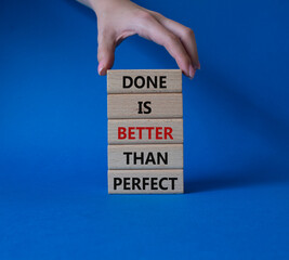 Wall Mural - Done is better than Perfect symbol. Wooden blocks with words Done is better than Perfect. Beautiful blue background. Businessman hand. Business and Done is better than Perfect concept. Copy space.