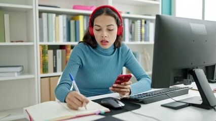 Poster - Young beautiful hispanic woman student using smartphone writing on notebook at university classroom