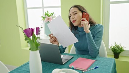 Sticker - Young beautiful hispanic woman talking upset on smartphone reading document at home