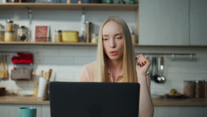 Woman accountant working remotely on laptop at kitchen. Manager looking computer