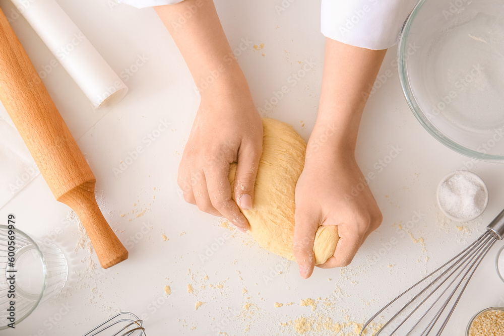 Woman kneading dough for Italian Grissini at white table in kitchen