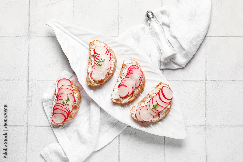 Plate with delicious radish bruschettas on white tiled table