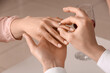 © Pixel-Shot - Man putting engagement ring on woman's finger, closeup