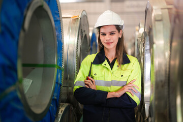 engineer woman standing with confidence with green working suite dress in front of warehouse of steel role material. smart industry worker operating. Industry maintenance engineer woman.