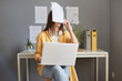 Tired exhausted woman working with documents and laptop having job troubles covering face with papers making mistake expressing negative feelings.
