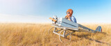 Fototapeta Koty - Little boy is playing the plane.
Happy and funy child imagines himself an aircraft pilot and plays in a aviator costume in an open-air field against a blue sky on a summer sunny day. 