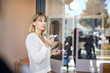 © Cavan Images - Blond female entrepreneur holding marker standing near glass wall