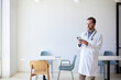 © Cavan Images - Male doctor using smart phone while standing in clinic