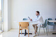 © Cavan Images - Side view of male doctor using tablet PC while sitting on chair