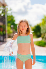 cute funny teenage girl in a swimsuit with an inflatable lifebuoy near the pool.