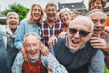 Joyful Seniors Taking a Group Selfie - Over-65 friends gathered at a countryside house, laughing and shouting together while capturing a festive moment.