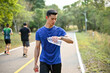 © bongkarn - A man checking his heart rate and running miles on his smartwatch while jogging in a park.