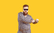 Plus size male model in funny pajamas having fun in studio. Bearded fat man wearing cool sunglasses and comfortable leopard PJs dancing isolated on yellow background. Fashion and crazy party concept