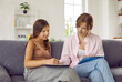 © Studio Romantic - Teen girl on theraphy session with young woman psychologist sitting next to her on sofa. She is writing making notes and talking to psychotherapist. Psychological help and support for teens concept.