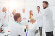 © ASDF - group of scientists congratulating their colleague in the workplace