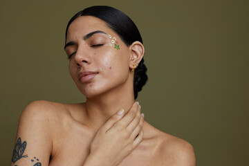 Wall Mural - Portrait of young woman with hand on neck against green background