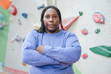 Canvas Print - Portrait of serious woman standing with arms crossed in front of climbing wall