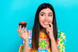 © deagreez - Photo of shiny doubtful woman dressed flower print t-shirt eating tasty cupcake looking empty space isolated blue color background
