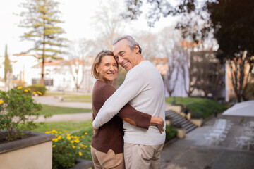 Happy Mature Spouses Hugging Standing In Park In Lisbon City