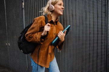 Woman in headphones smiling while walking through city street