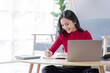 © David - Beautiful Young asian woman at home sitting on the sofa while using laptop and headphone at home