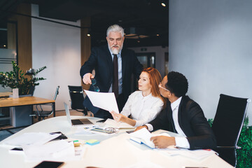 Wall Mural - Multiethnic coworkers reading papers with male leader in office