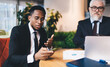 © BullRun - Black businessman with cellphone working in office