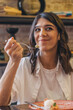 © Tatyana - Portrait of a happy young attractive dark-haired woman eating in a cafe.