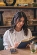© Tatyana - A young attractive dark-haired woman is reading a book in a cafe.