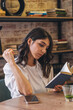 © Tatyana - A young attractive dark-haired woman is reading a book in a cafe.