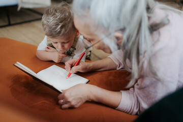 Wall Mural - Grandmother drawing in a notepad with her little grandson.