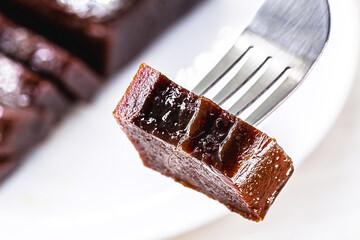 Sticker - piece of guava jam on a fork. Blurred guava in the background. Space for text, sweet made from fruit, traditional of the June festivities in Brazil, rural food