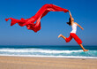 © Designpics - Beautiful young woman jumping on  the beach with a colored tissue