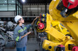 © Wosunan - A female engineer installs a program on a robotics arm in a robot warehouse. And test the operation before sending the machine to the customer.