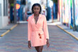 © Oren Thomas - Young woman wearing a blazer dress walking on a paved brick street in Downtown Kingston, Jamaica