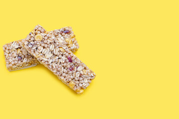 Two muesli bars on a yellow bright background. Healthy sweet dessert snack. Cereal muesli with nuts, oatmeal and berries on a yellow background. Delicious and healthy dessert. Free space for text