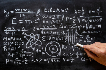 Operaciones y formulas de física cuántica escritas a mano con una tiza en la pizarra