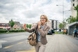 © Miljan Živković - mature woman stand at city bus stop use smartphone while wait drive