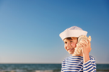 Poster - Happy child listen seashell on the beach