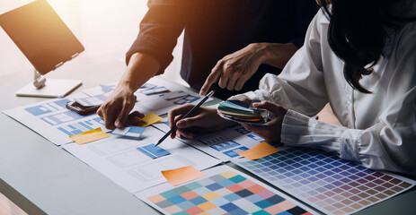 Close up ux developer and ui designer brainstorming about mobile app interface wireframe design on table with customer breif and color code at modern office.Creative digital development agency