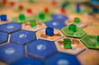 Żetony oraz elementy gry planszowej Terraformacja Marsa, widoczne niebieskie i brązowe płytki oraz niebieskie, zielone i czerwone kostki