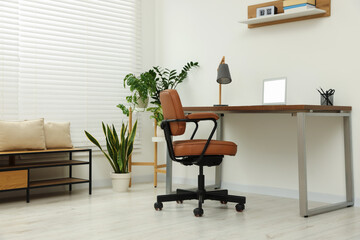 Poster - Stylish office interior with comfortable chair, desk, laptop and houseplants