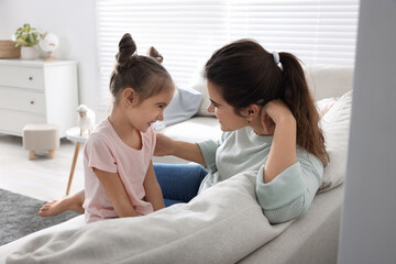 Wall Mural - Young mother and her daughter spending time together on sofa at home