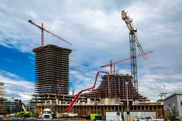 Wall Mural - Large construction site with construction cranes working on a building complex, Work is progressing towards the completion of the upper floors of the buildings