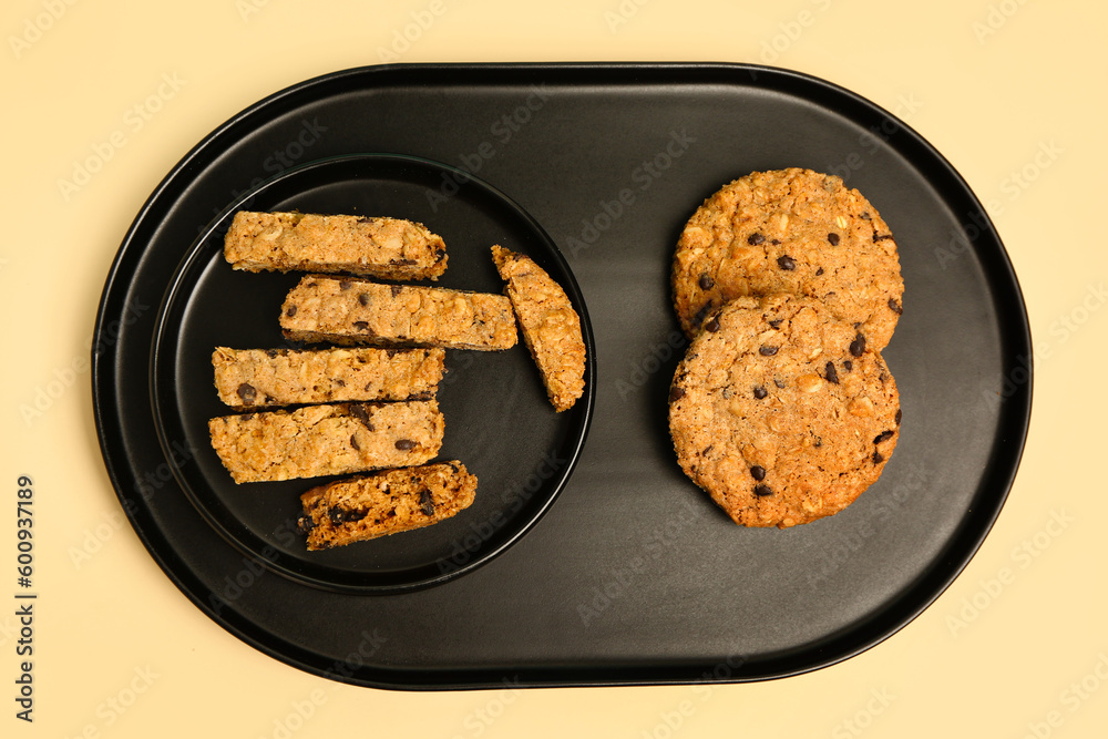 Tray and plate with tasty biscotti cookies on beige background