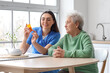 © Pixel-Shot - Young caregiver and senior woman taking pills in kitchen