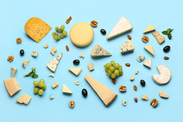 Different types of tasty cheese, nuts and grapes on blue background